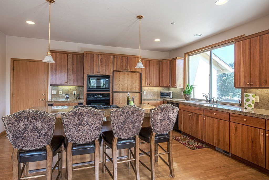 Bright kitchen with an island, upholstered bar stools and warm wood cabinets