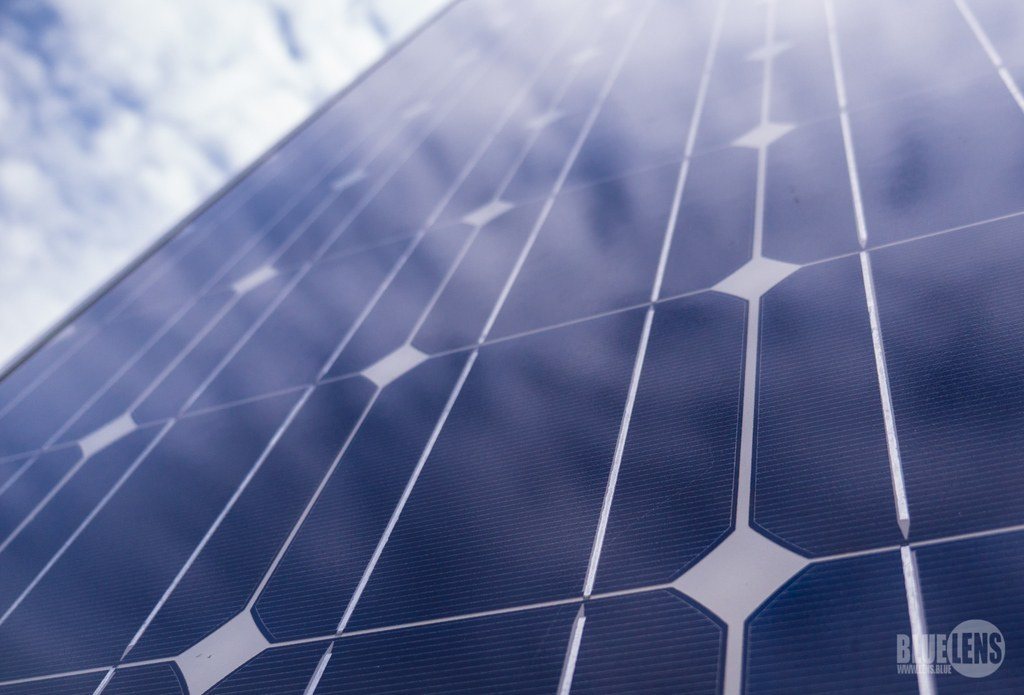 Close view of solar panels reflecting a blue sky with soft clouds